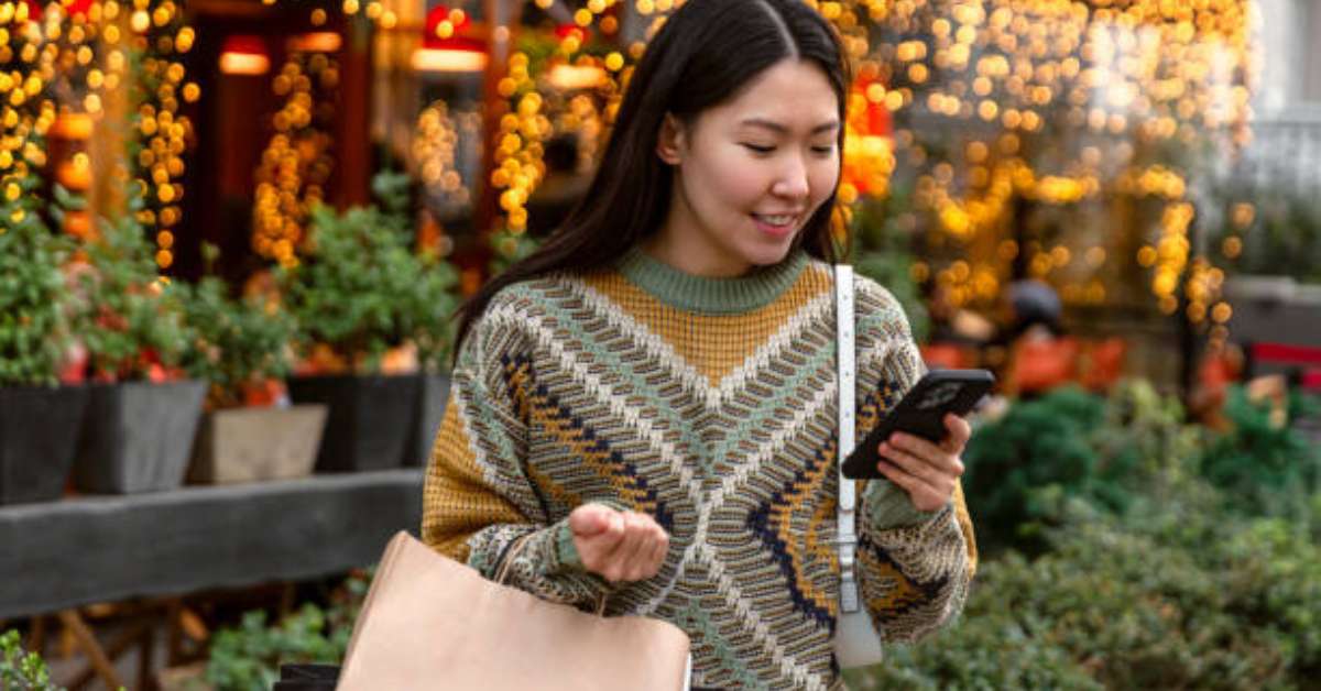 Woman stares at her phone standing outside viewing her customer loyalty points for a retail store.