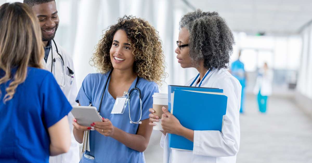 A group of doctors in a medical facility are discussing a report from a tablet.