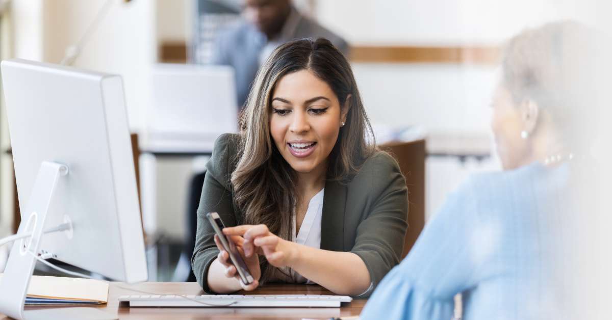 Woman shows teller her banking account information on the newly developed app.