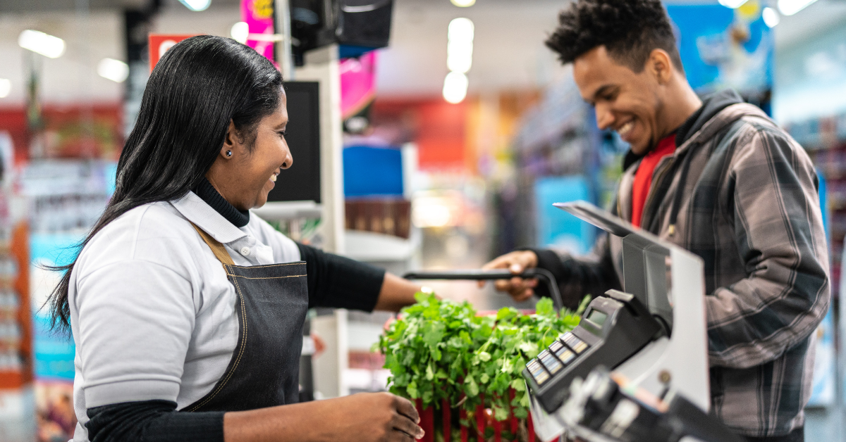 A man and woman stand at a grocery checkout ringing up items.