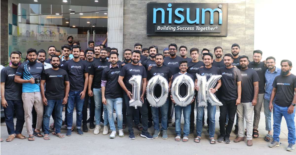 A group of Nisum employees holding a silver 100k balloon in celebration of reaching 100k LinkedIn followers